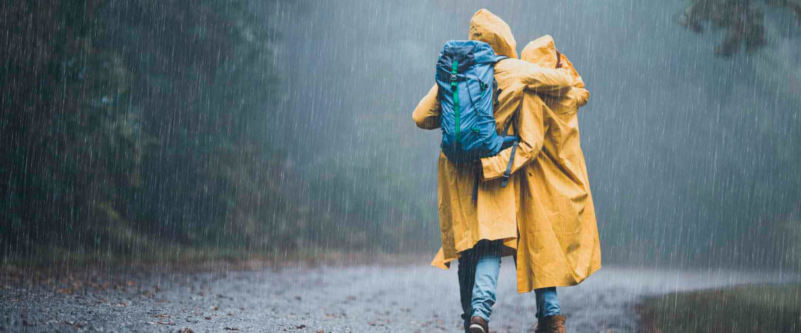 Pariskunta kävelee satessaa keltaisissa sadetakeissa
