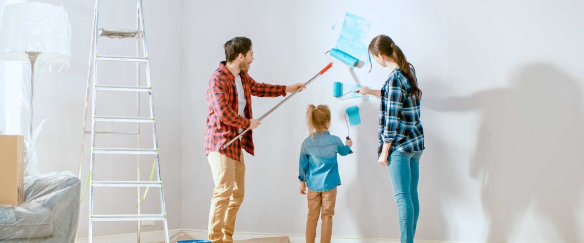 Perhe maalaa uudessa kodissa seinää siniseksi