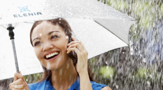 Nainen puhuu kännykkään sateenvarjon alla