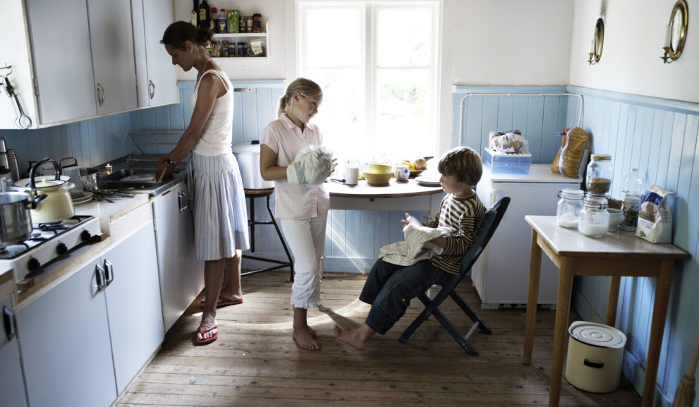 Keittiössä äiti ja kaksi lasta tiskaavat.