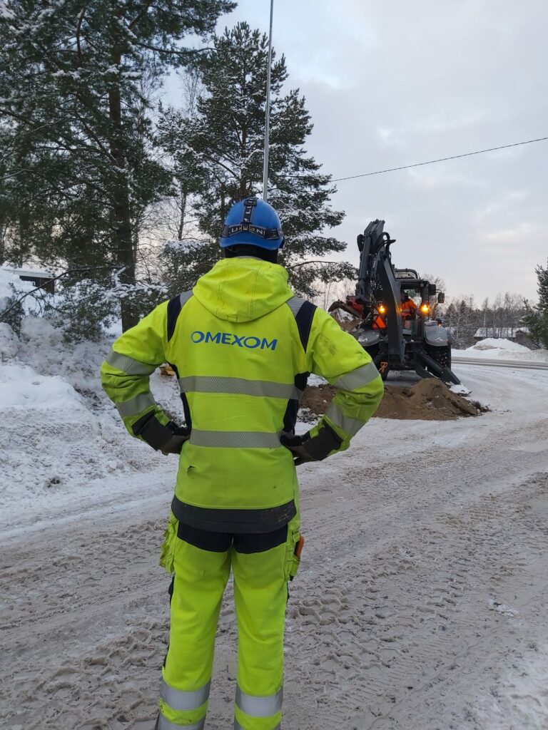 mies työvaatteissa, joissa selässä lukee Omexom