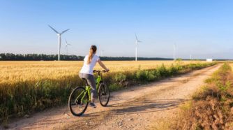 Nainen pyöräilee maaseudulla tuulipuiston ohi